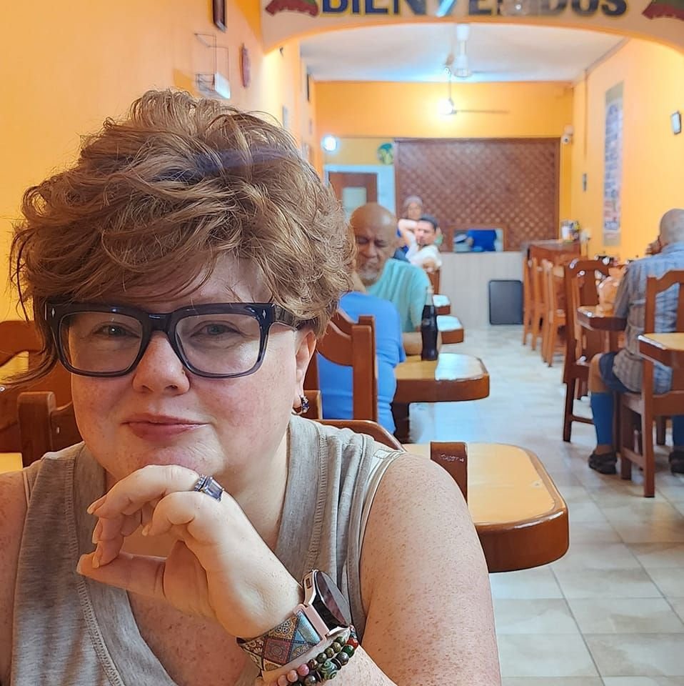 Renee Shupe, sitting in a sunny cafe with her chin on her hand
